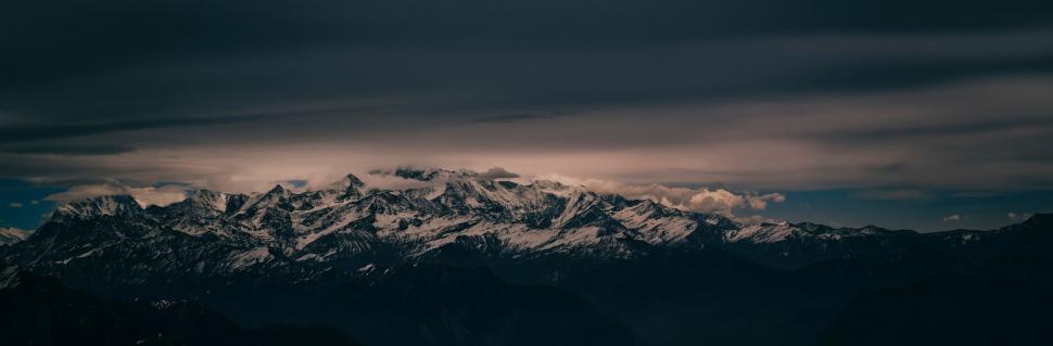 Free Image of A snowy mountain tops with clouds in the sky 