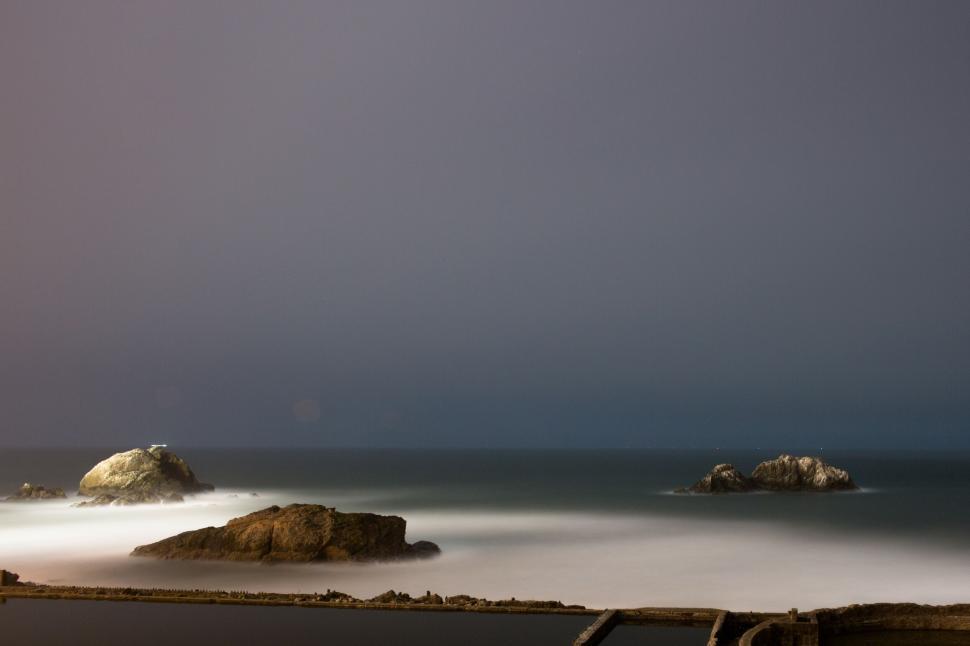 Free Image of A body of water with rocks and a dock 