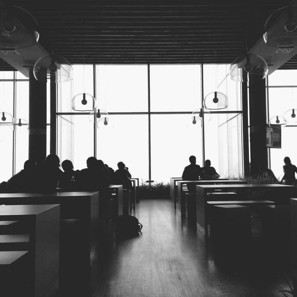 Free Image of A group of people sitting in a room with large windows 