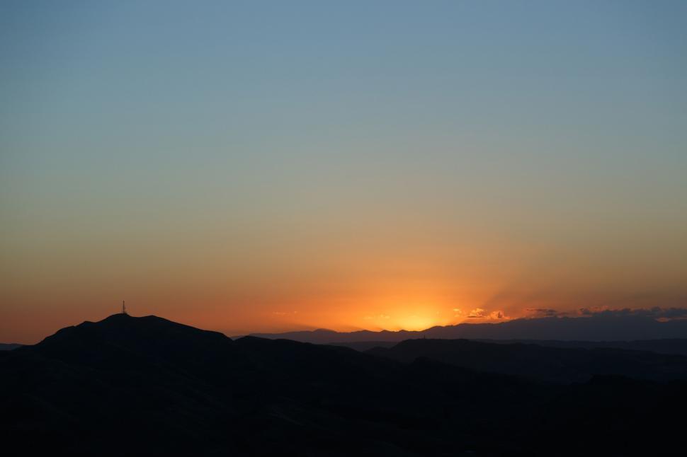 Free Image of A sunset over a mountain 