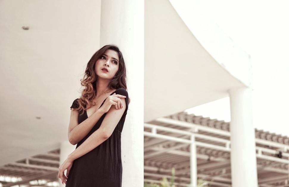 Free Image of A woman leaning against a pillar 