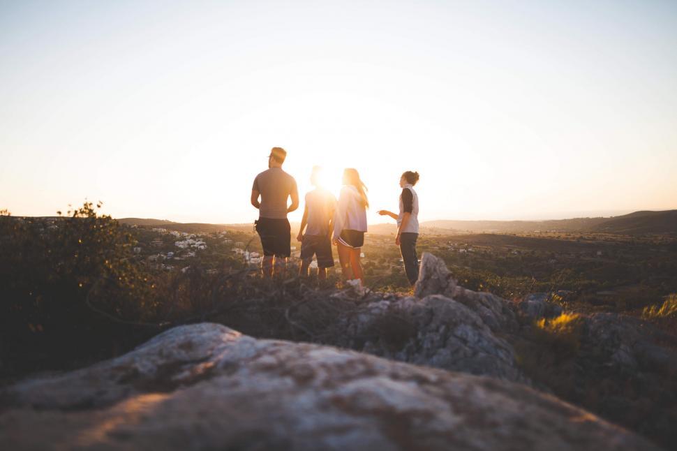 Free Image of A group of people standing on a rock looking at a city 
