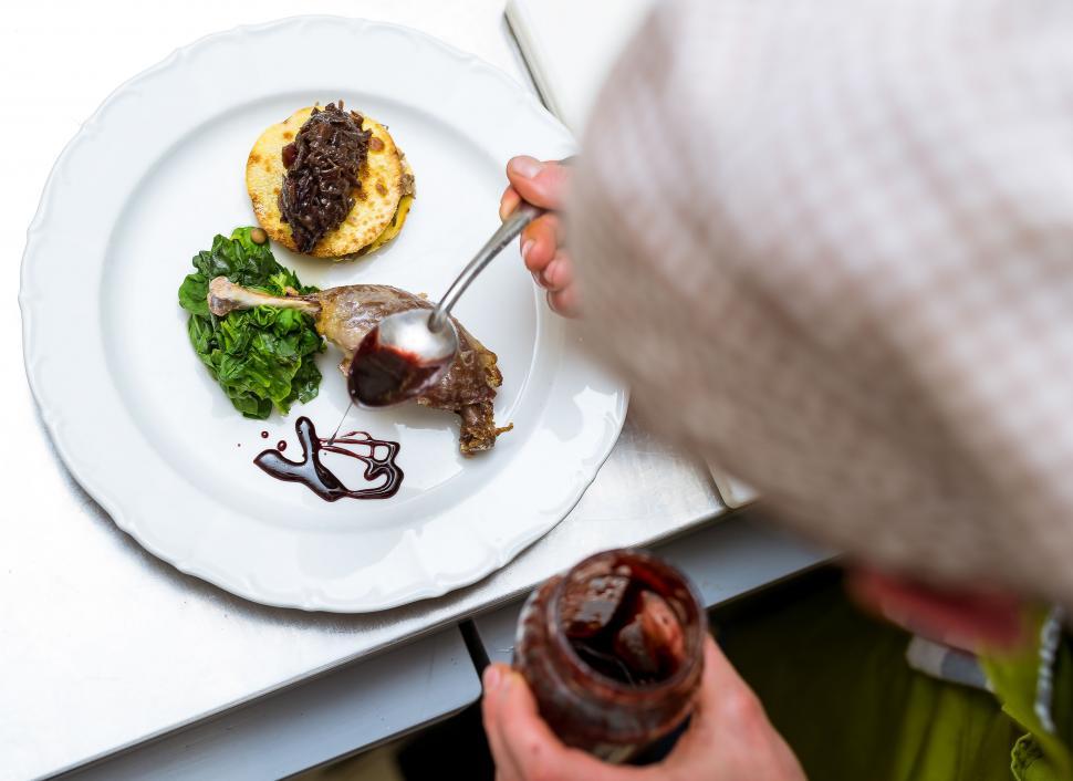 Free Image of A person pouring sauce on a plate of food 