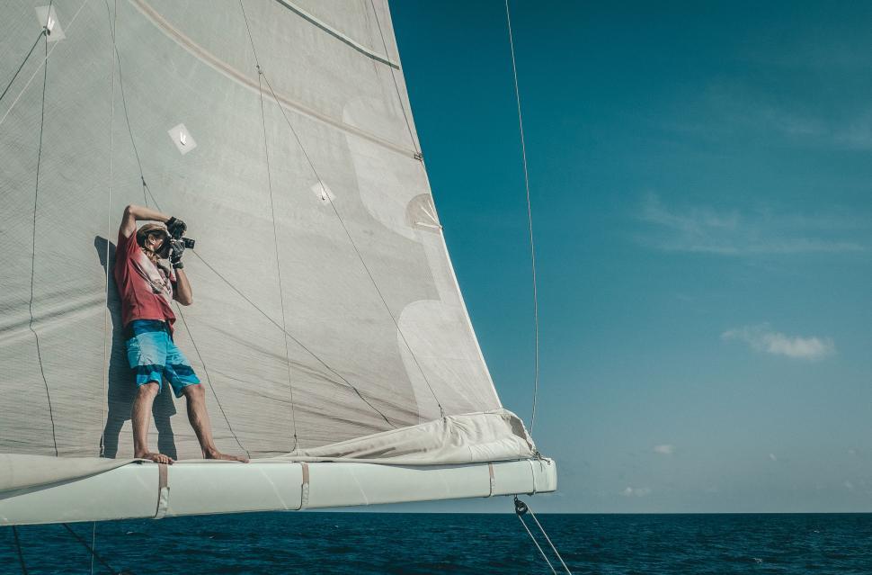 Free Image of A man taking a picture of a sailboat 