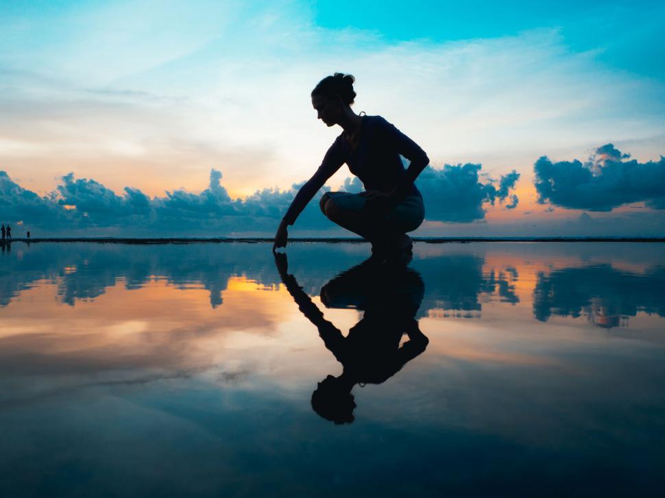 Free Image of A woman kneeling on a beach 