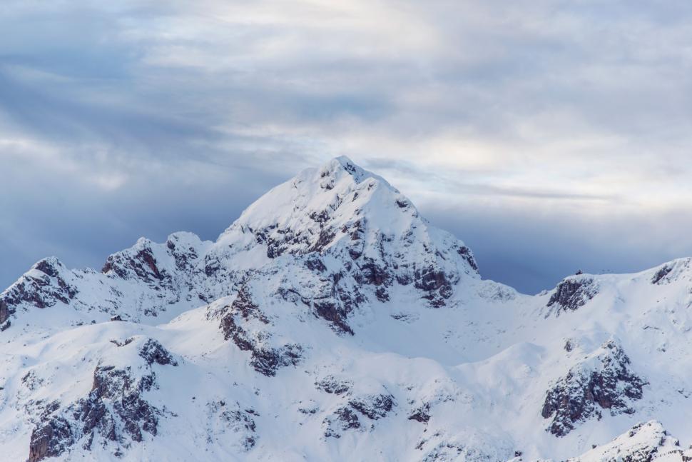 Free Image of A snowy mountain tops with clouds in the sky 