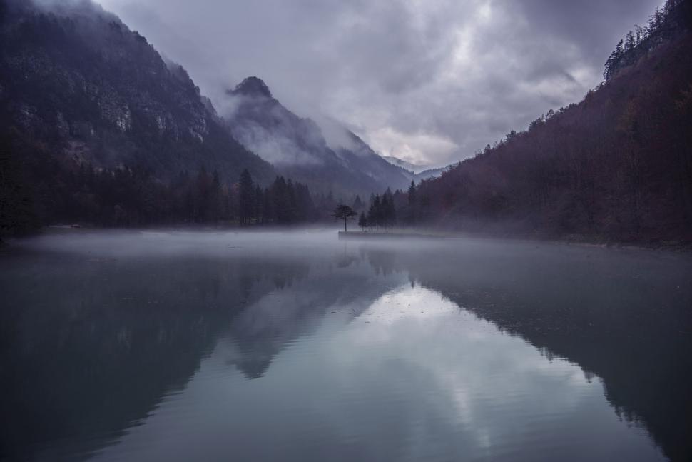 Free Image of A lake with trees and mountains in the background 