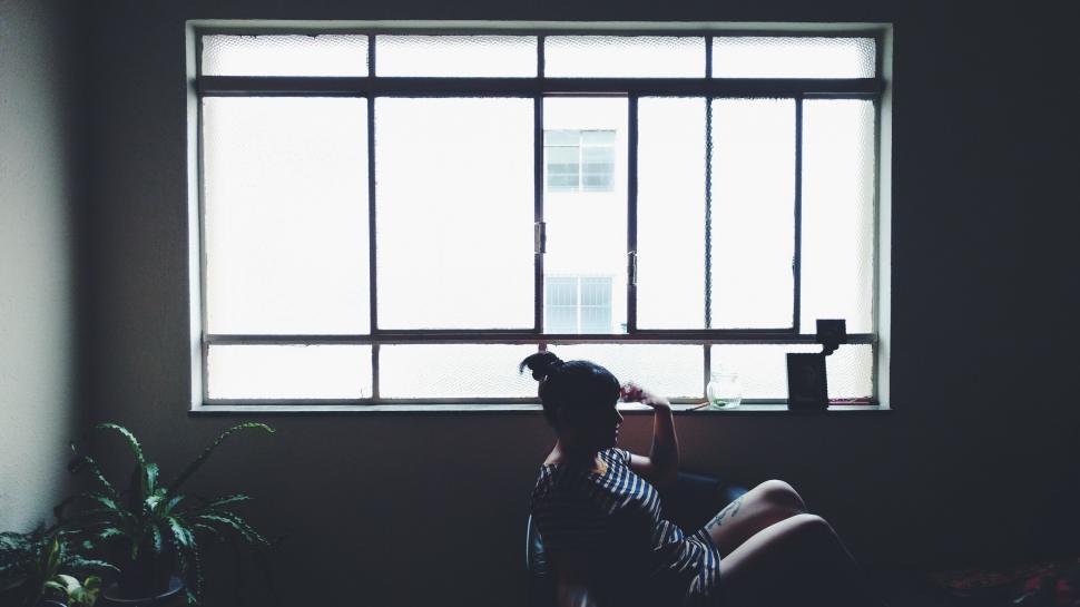 Free Image of A woman sitting in a chair by a window 