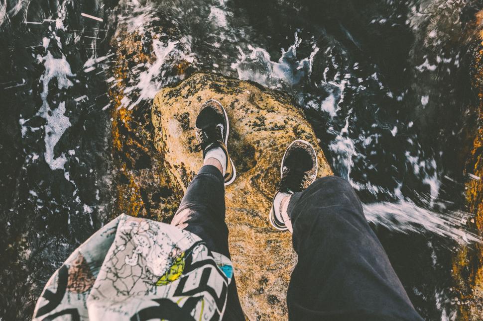 Free Image of A person s legs on a rock above water 