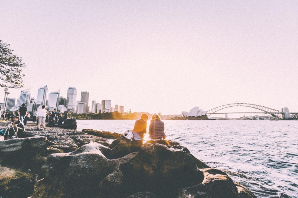 Free Image of Two people sitting on a rock by the water 