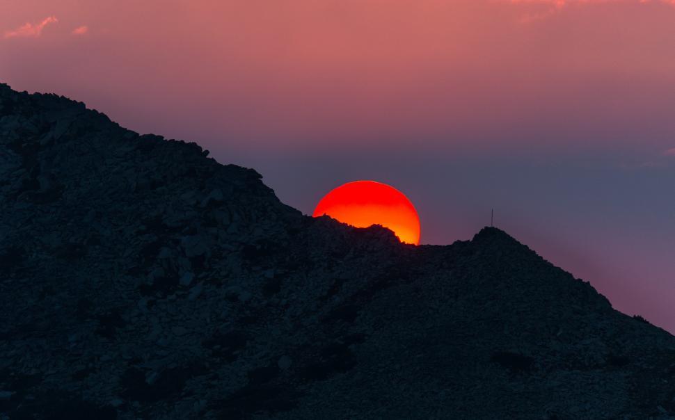 Free Image of A sunset over a mountain 