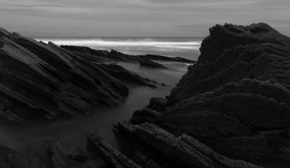 Free Image of A rocky beach with waves crashing on it 