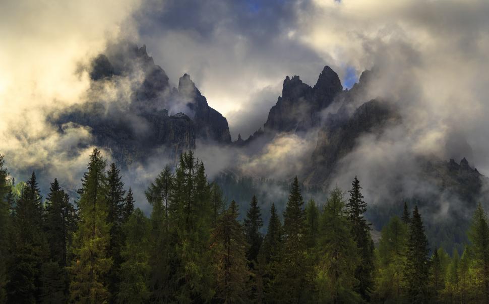 Free Image of A mountain range with trees and clouds 
