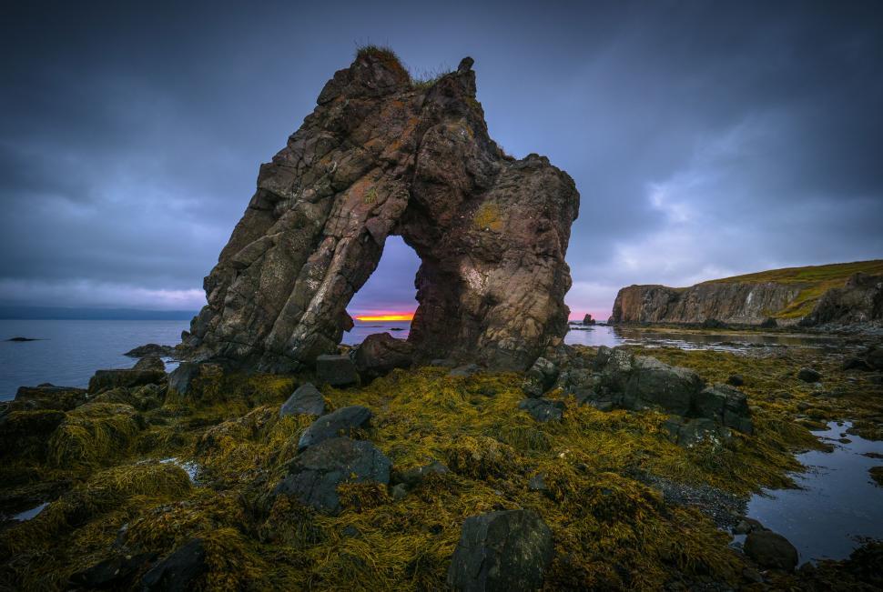Free Image of A rock formation with a hole in the middle of the ocean 