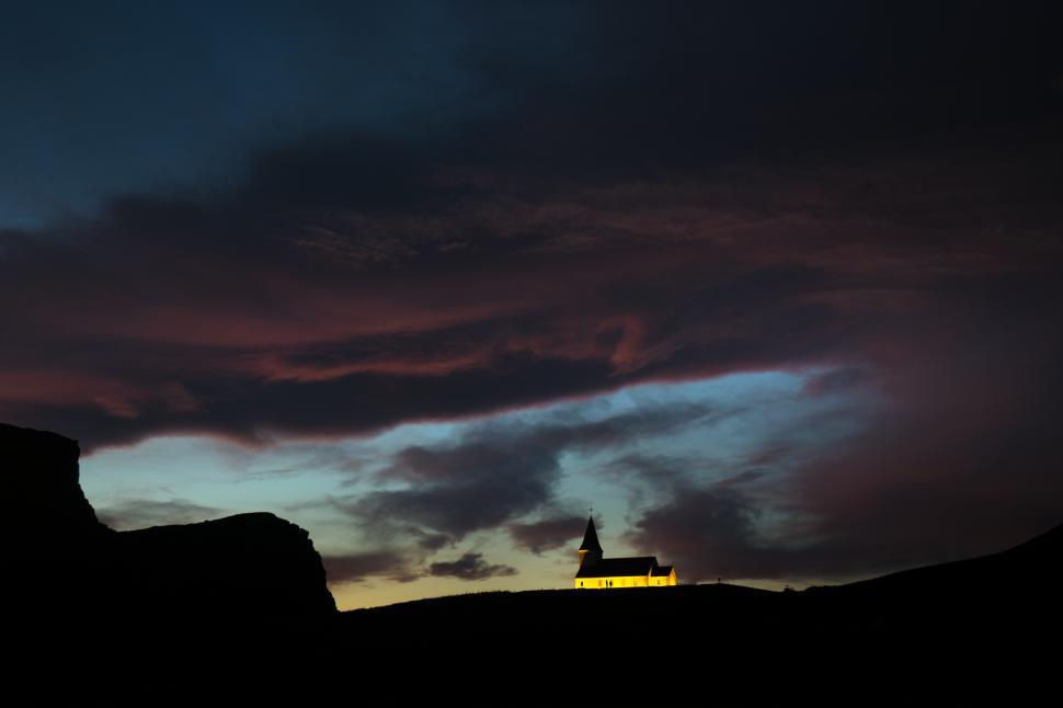Free Image of A building on a hill with a steeple and a cloudy sky 