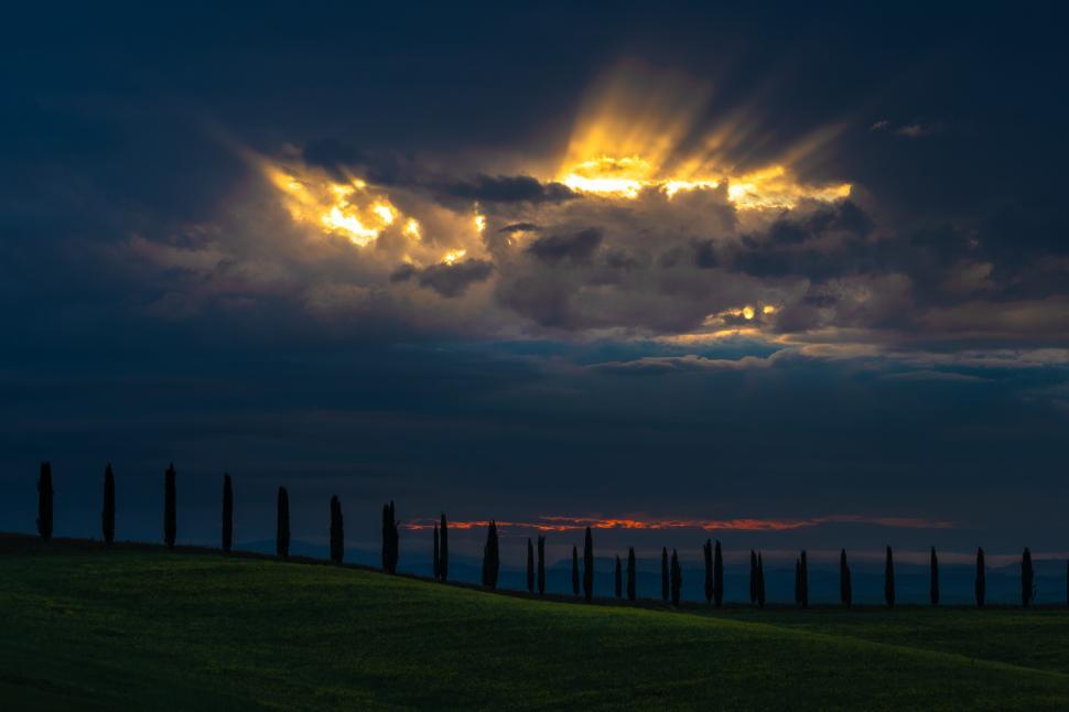 Free Image of A sun shining through clouds over a field of grass 