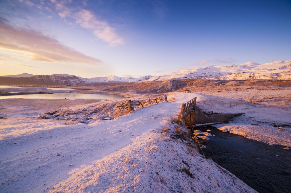 Free Image of A snowy landscape with a river and a bridge 