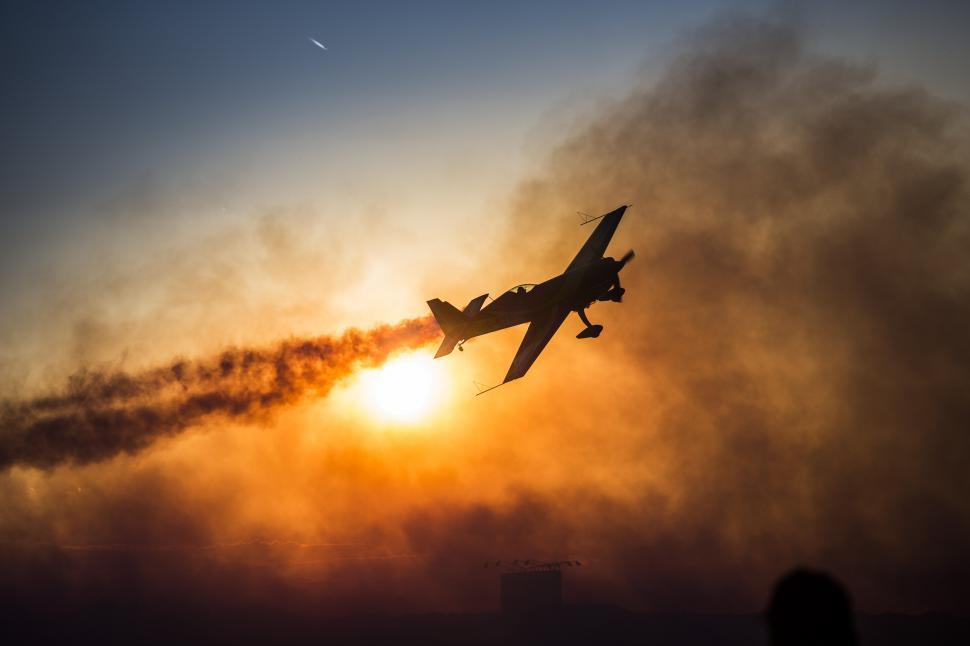 Free Image of A plane flying in the sky with smoke coming out of it 