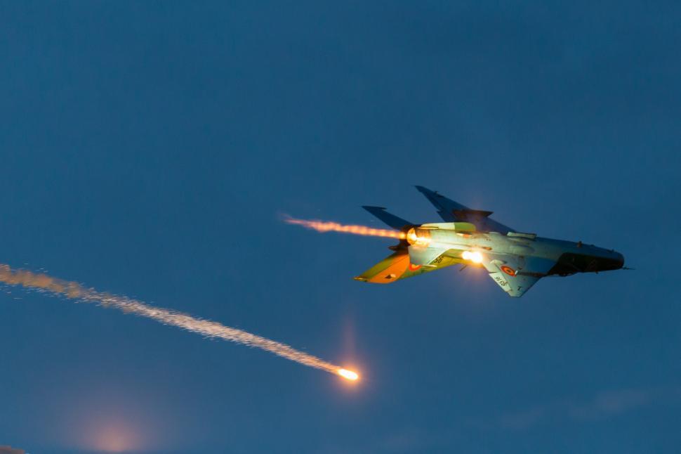 Free Image of A jet flying in the sky with two rockets shooting 
