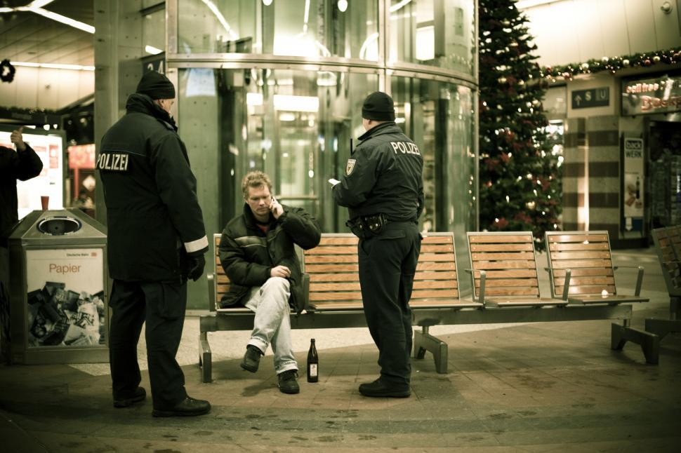 Free Image of A man sitting on a bench with a man in the back 