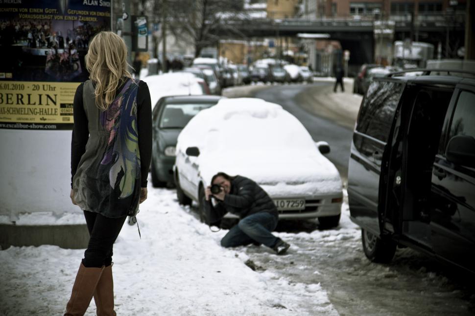 Free Image of A man taking a picture of a car in the snow 