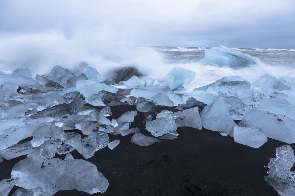 Free Image of Ice on a beach with waves crashing 