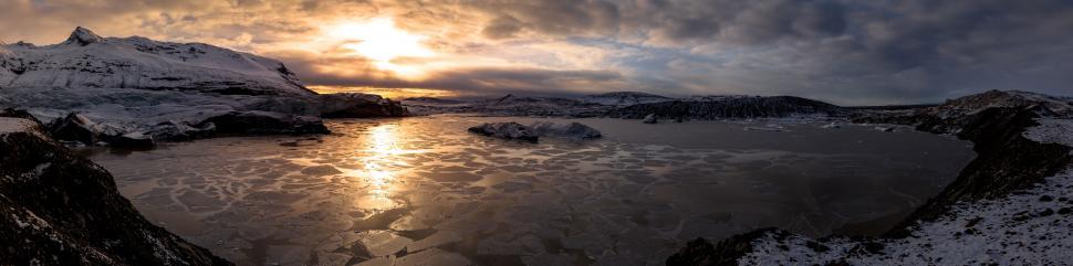 Free Image of A frozen lake with ice and mountains in the background 