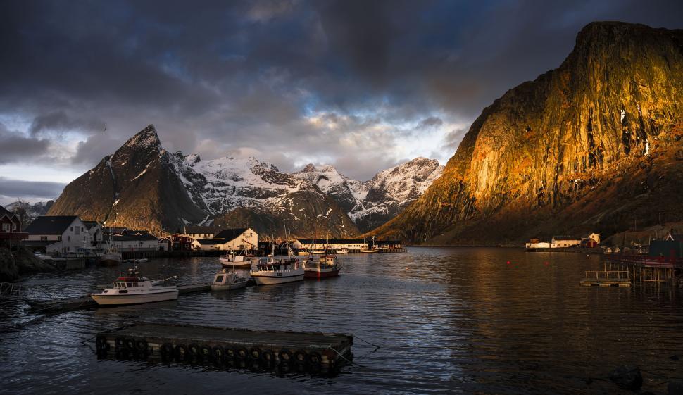 Free Image of Boats in a body of water with a dock and mountains in the background 