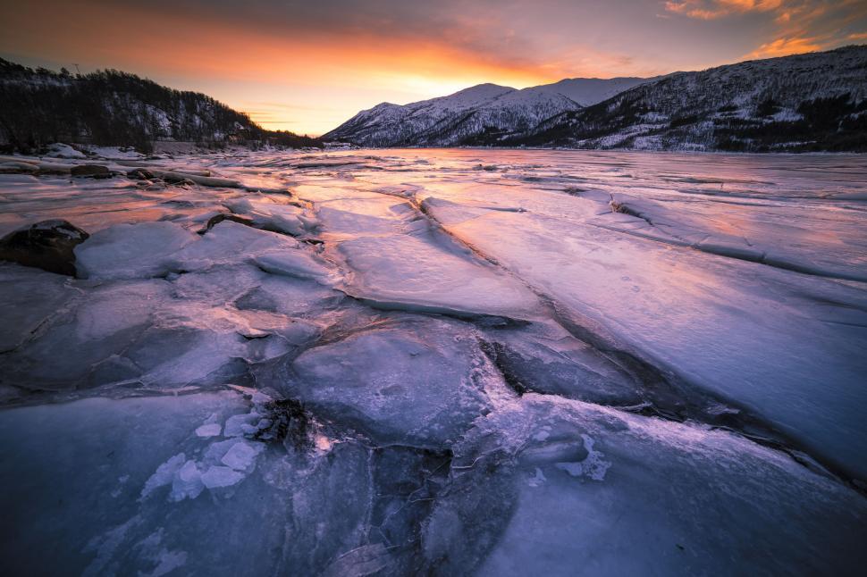 Free Image of A frozen lake with mountains in the background 