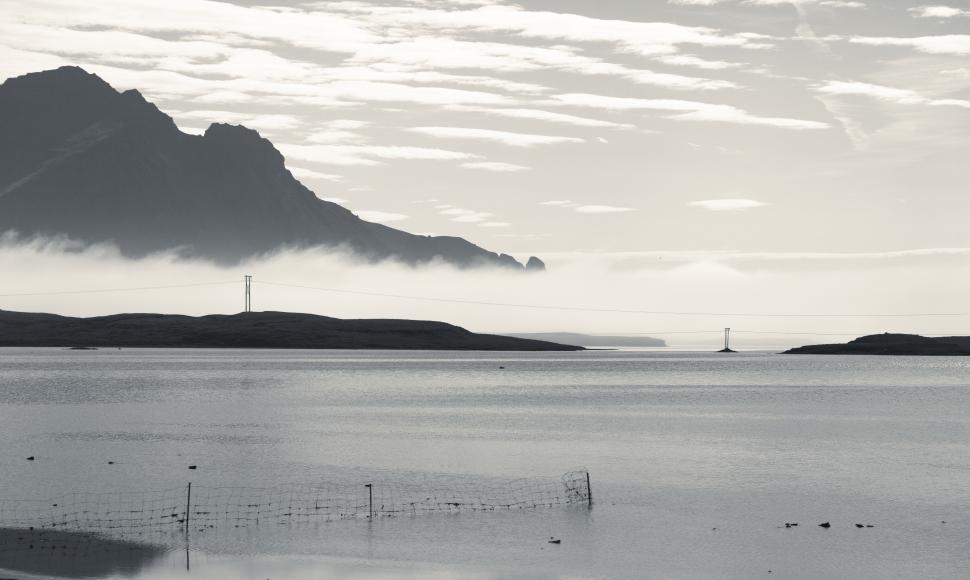 Free Image of A body of water with a fence and a mountain in the background 