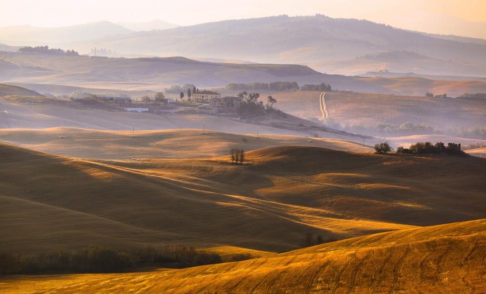 Free Image of A rolling hills with a house and trees 