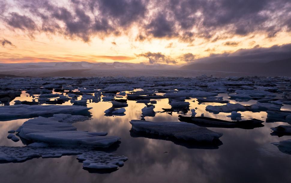 Free Image of Ice floating ice in water with mountains in the background 