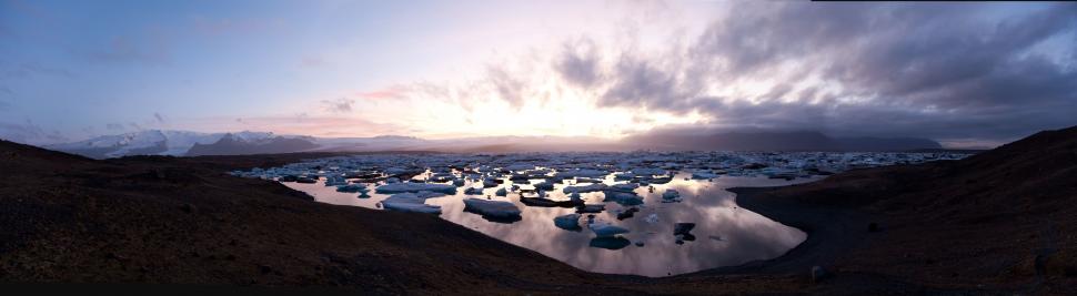 Free Image of Icebergs floating in water with mountains in the background 