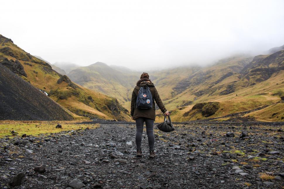 Free Image of A woman standing on a rocky area with mountains in the background 