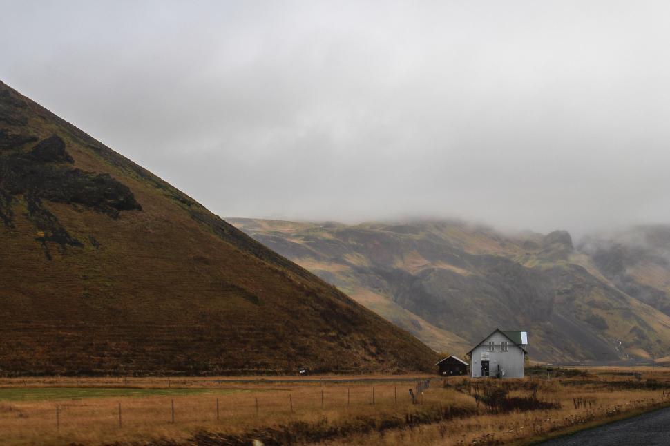 Free Image of A house in a field with a hill in the background 