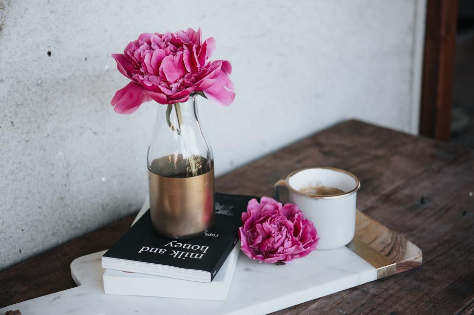 Free Image of A pink flower in a vase on a stack of books 