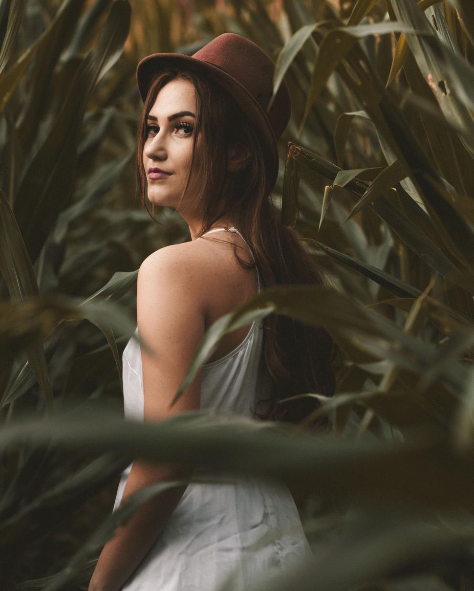 Free Image of A woman in a hat in a field of tall grass 