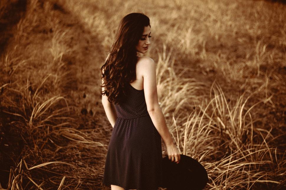 Free Image of A woman in a dress holding a hat 