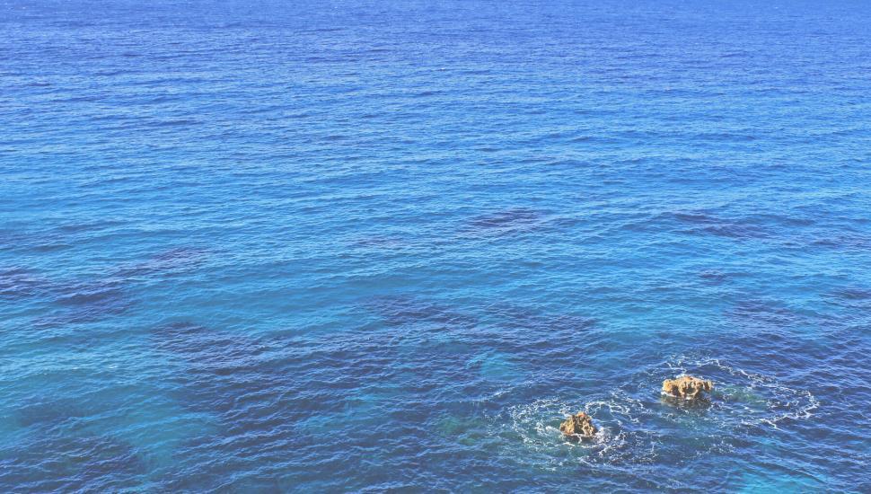 Free Image of A blue ocean with rocks in it 