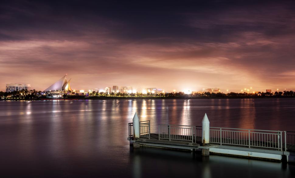 Free Image of A dock on a body of water with a city in the background 