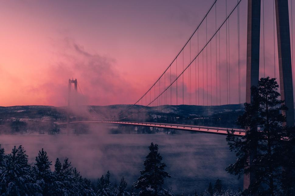 Free Image of A bridge over water with fog and trees 