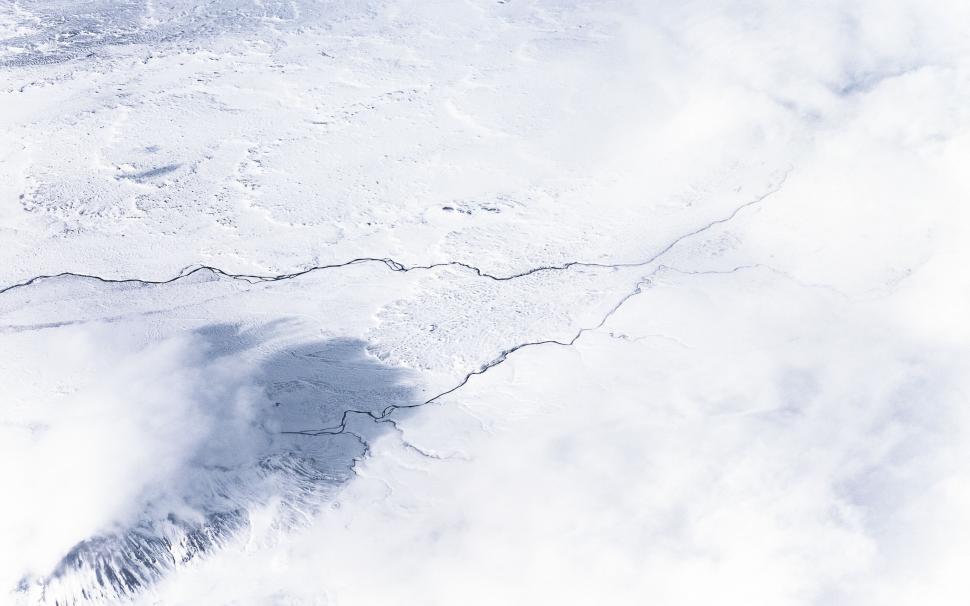 Free Image of A snow covered ground with a crack in the ground 