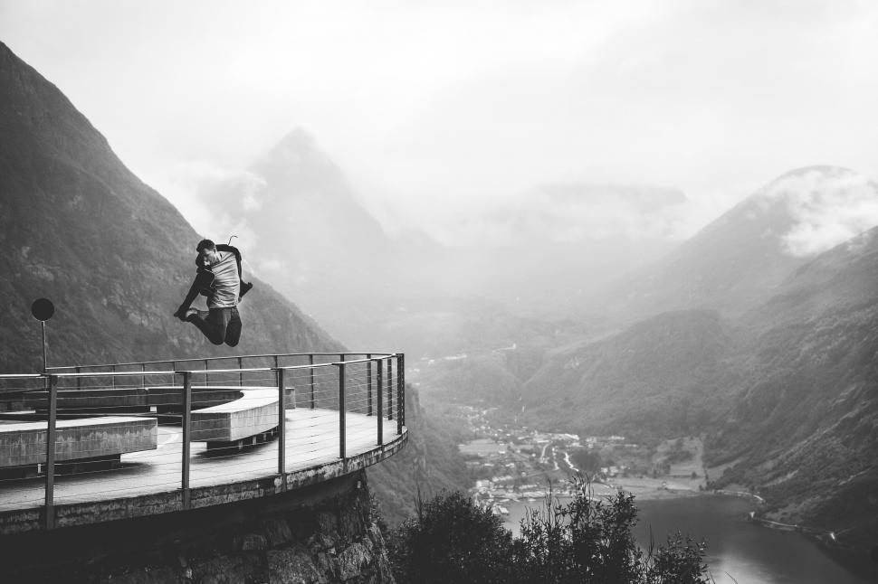 Free Image of A man jumping off a bridge over a mountain 