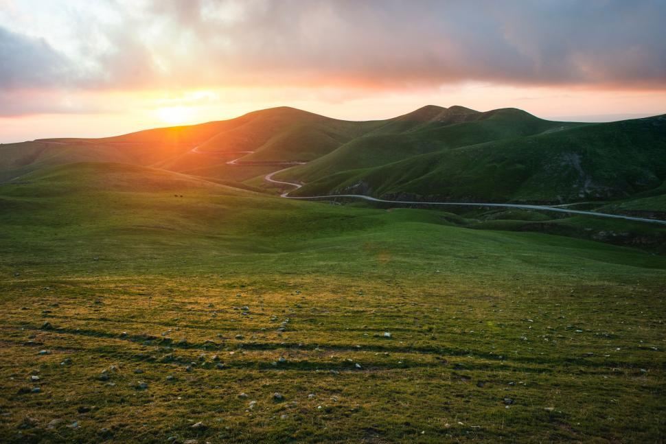 Free Image of A green hills with a road and a road 