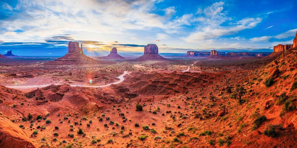 Free Image of A landscape of a desert with a road and tall rock formations 