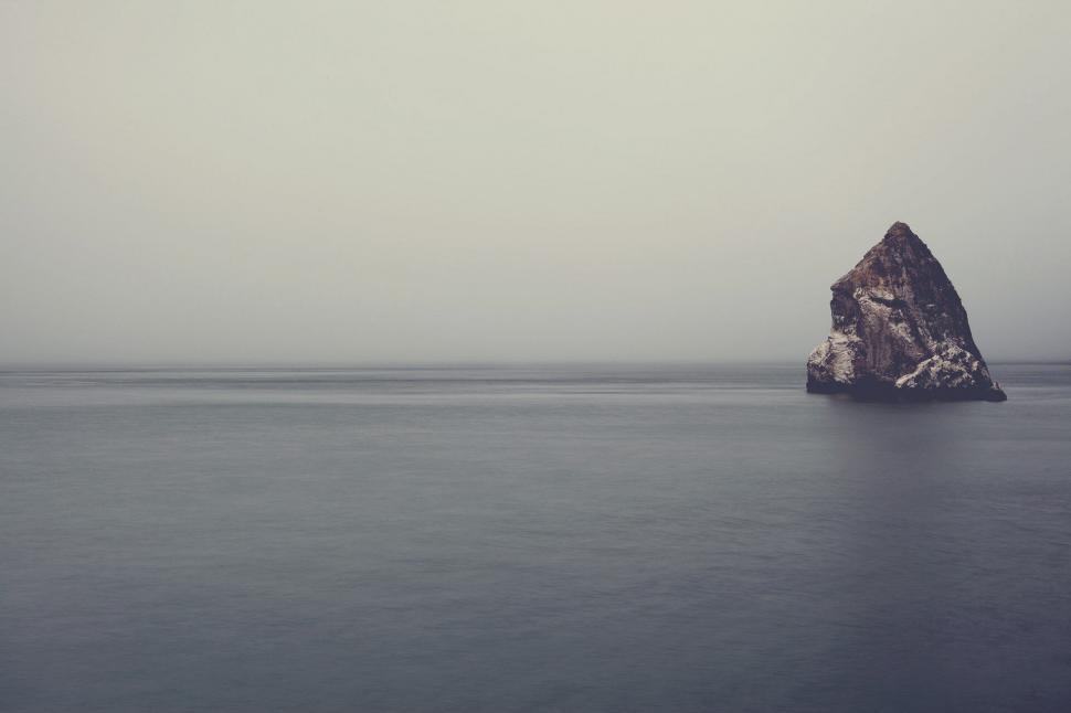 Free Image of A large rock in the middle of a body of water 