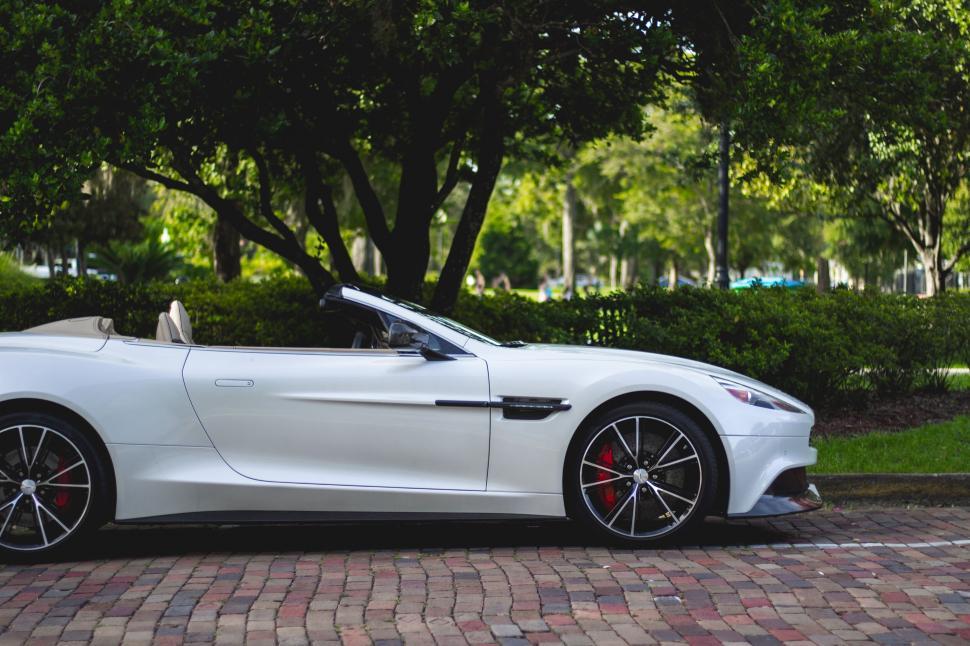 Free Image of A white convertible car parked on a brick road 