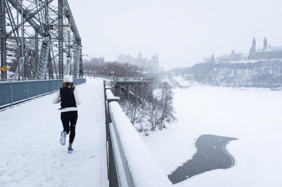 Free Image of A person running on a bridge in the snow 