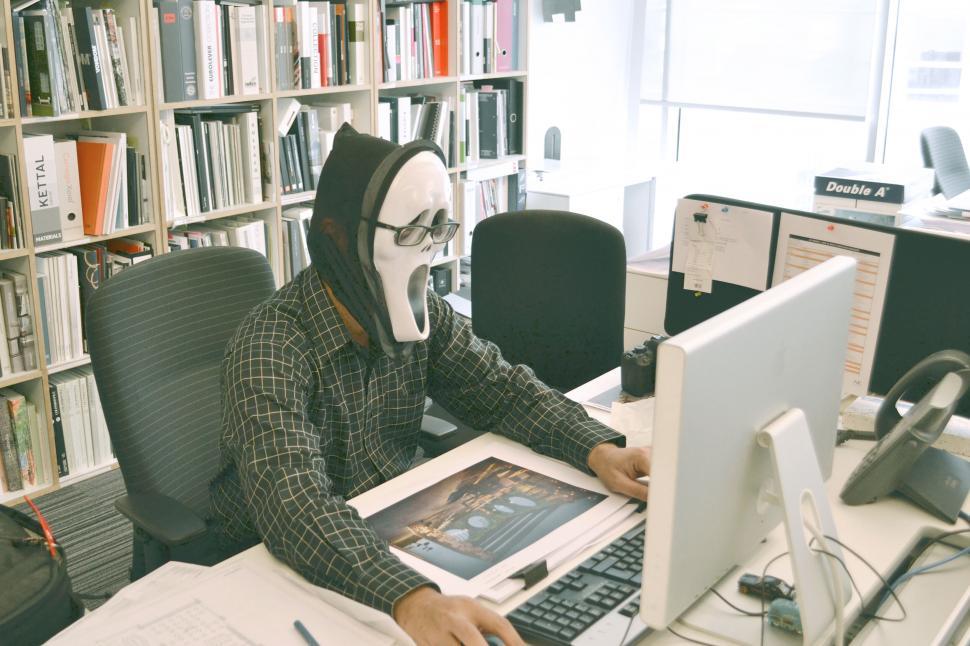 Free Image of A man wearing a mask and glasses sitting at a desk 