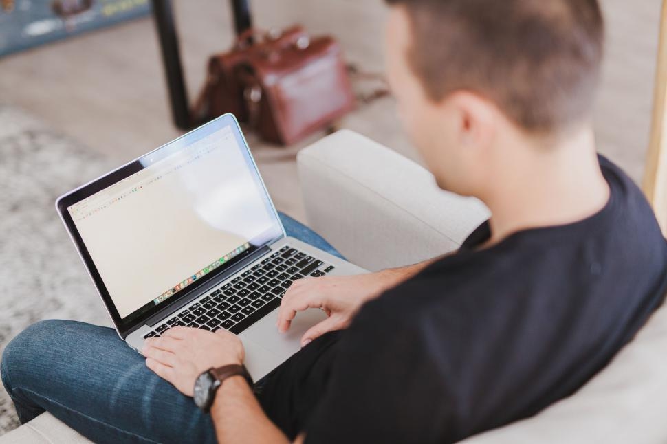 Free Image of A man sitting on a couch using a laptop 